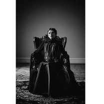 zdjęcie przedstawia kobietę w czarnej sukni siedzącą na wysokim czarnym fotelu