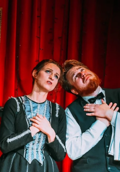 Mężczyzna i kobieta, stojący obok siebie z uniesionymi twarzami ku górze i złożonymi rękami na piersiach.