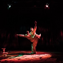 Dwie osoby stojące bardzo blisko siebie, oświetlone czerwonym światłem na czarnym tle.