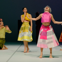 Zdjęcie dwóch tancerek w kolorowych spódnicach i topach na scenie