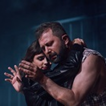 Kobieta i mężczyzna w uścisku, mężczyzna patrzy na swoje dłonie. Ciemno-niebieskie tło.