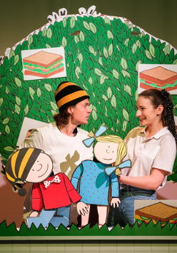 Zdjęcie przedstawiające dwóch aktorów na scenie z lalkami Gapiszona i Zuzi. W tle makieta drzewa.
