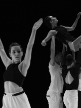 Czarno-białe zdjęcie tancerzy. Na pierwszym planie młoda kobieta z uniesionymi rękami do góry, na drugim planie trzy osoby unoszą kobietę na wyciągniętych do góry rękach.