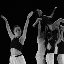 Czarno-białe zdjęcie tancerzy. Na pierwszym planie młoda kobieta z uniesionymi rękami do góry, na drugim planie trzy osoby unoszą kobietę na wyciągniętych do góry rękach.