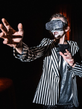 Zdjęcie kobiety w goglach na oczach z wyciągnietymi przed siebie rękoma.