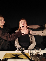 Na zdjęciu trzy osoby, dwie trzymają za szyję osobę w środku, dusząc ją.