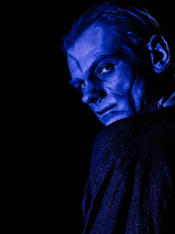 Zdjęcie mężczyzny oglądającego się przez ramię, jego twarz oświetla niebieskie światło.