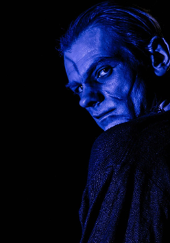 Zdjęcie mężczyzny oglądającego się przez ramię, jego twarz oświetla niebieskie światło.