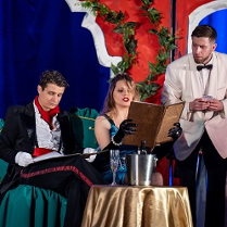 Przy stoliku siedzą kobieta i mężczyzna, oboje trzymają menu. Obok nich stoi kelner, który czeka na zamówienie.