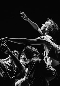 Czarno-białe zdjęcie mężczyzny z uniesionymi rękoma, który podtrzymywany jest przez kilka osób.