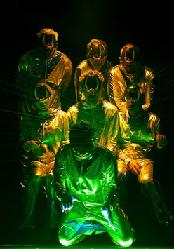 Kilka osób w skafandrach i maskach oświetlonych zielono-żółtym światłem.