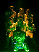 Kilka osób w skafandrach i maskach oświetlonych zielono-żółtym światłem.