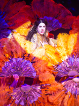 Kobieta wśród wachlarzy z kolorowych piór.