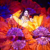 Kobieta wśród wachlarzy z kolorowych piór.