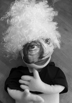 Zdjęcie szmacianej lalki z maską przypominającą kobietę, w peruce z kręconymi włosami.