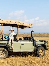 Otwarty samochód terenowy na sawannie, a na nim dwójka dzieci.