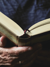 Zdjęcie, otwarta książka trzymana przez dłonie człowieka