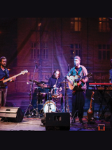 Czterech członków zespołu na scenie w trakcie koncertu.