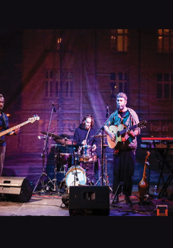 Czterech członków zespołu na scenie w trakcie koncertu.