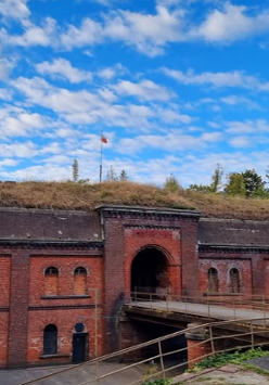 Wejście do starego, wojskowego fortu przez kładkę przewieszoną nad suchą fosą.
