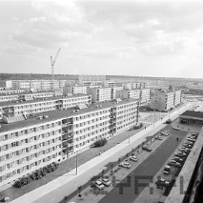 A black and white photo of a housing estate. A car park is in the foreground.