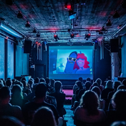 A darkened hall, full of viewers. An animated film is displayed on the screen.