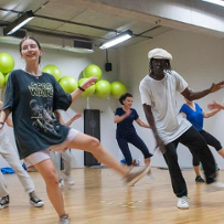A group of dancing people in similar poses. As a background - green balls hanging at the wall.