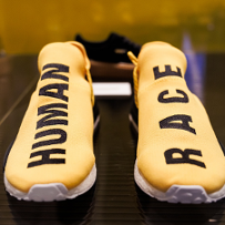 A pair of yellow sneakers. One has the word "human" written in black on it, the other has the word "race" written on it.