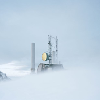 An object with a large, round lamp in a snowy, foggy wasteland.