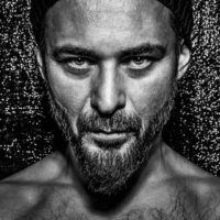 Black and white photo of the artist - face of a man looking into a camera