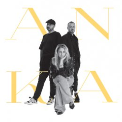 Photo of Ania Światczak sitting on chair. Two man standing behind her.