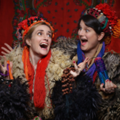 Photo of two laughing young women in folk costumes.