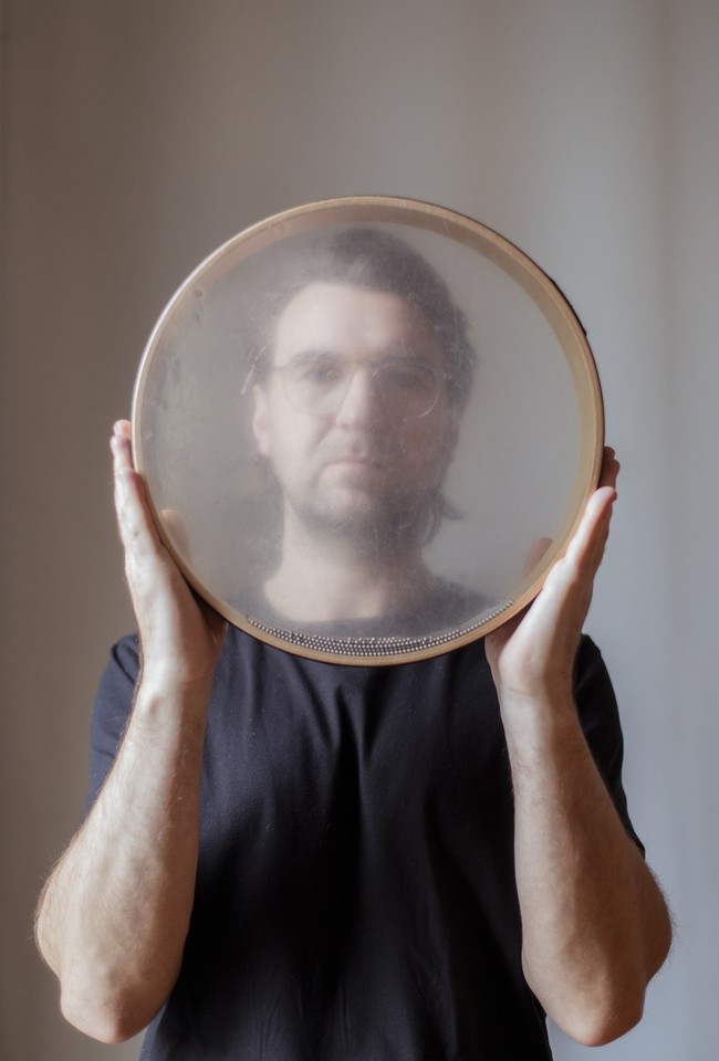 Picture of Krzysztof Dysa - a man holding a round object tat looks like a tambourine in front of him.