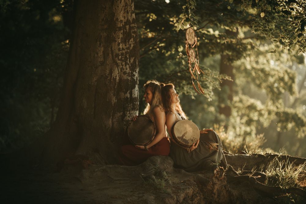 Two women sitting under the tree, back to back.