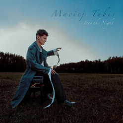 Phto of Maciej Tubis, sitting on a chair on a field, trees as a background.