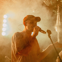 Photo of a young man singing to a microphone.