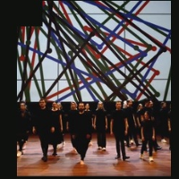 Photo of a group of people dressed black on stage. A colourful visualization in the background.