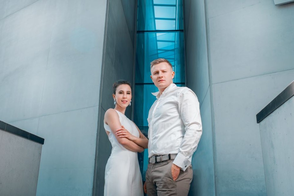 Photo of the performers: a man and a woman in front of the building