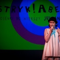 Photo from the concert: a woman singing to a microphone, blue and green background.