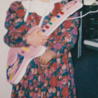 One of the exhibition works: a child, with its face unvisible, holding a toy guitar.