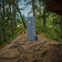 One of the exhibition works: a metal object standing on a path in a forest.