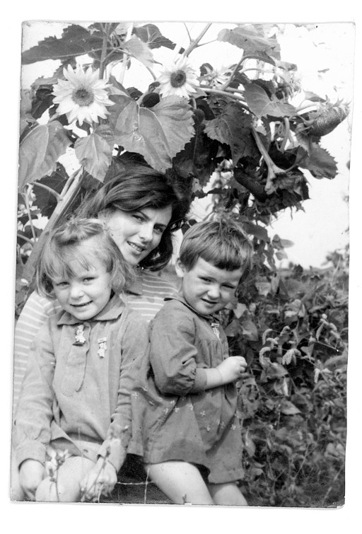 Black and white photo of a young woman and two kids; sunflowers as a background