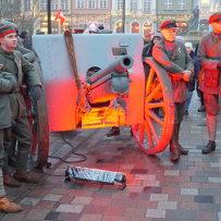 Four men in insurgent costumes stand next to a cannon.
