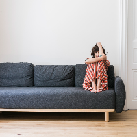 Picture of Katarzyna Groniec, who is sitting with her legs curled up in a couch's corner.