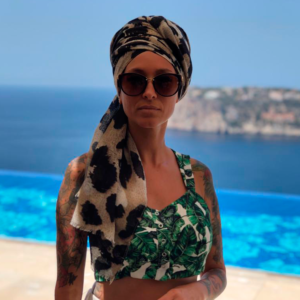 Photo of the singer - a woman in sunglasses; the sea in the background.