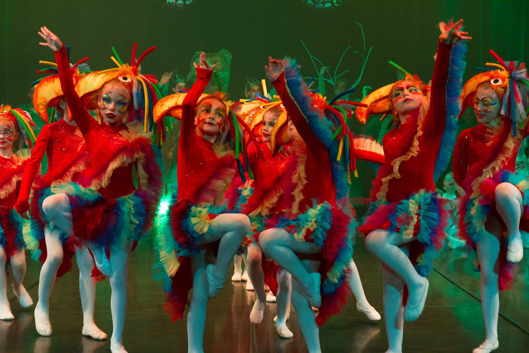 Photo of children in colourful clothes performing on stage.