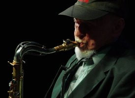 Dark photo of the musician: a man playing the saxophone