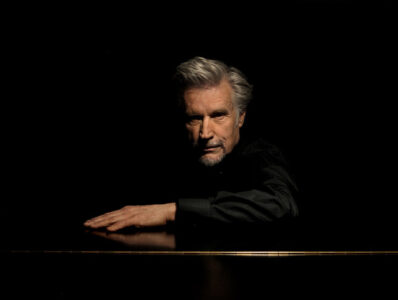 Photo of the artist - a man in black clothes on the black background