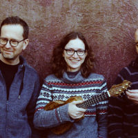 Photo of band members - one woman holding ukulele between two men