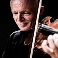A photo of the artist - a man playing the violin